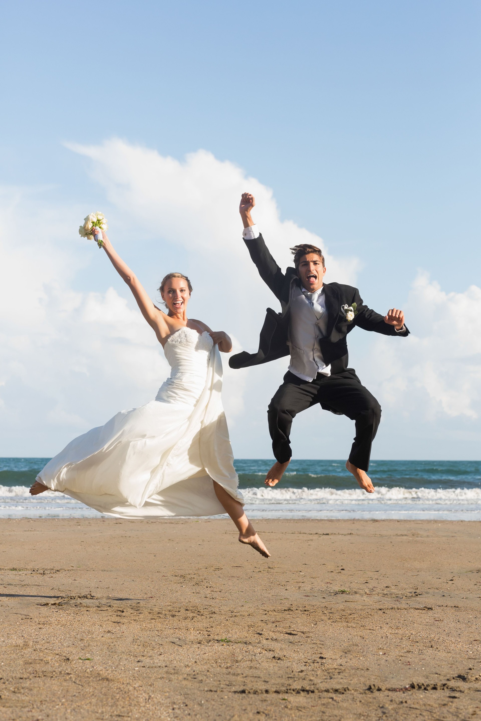 Delighted lovely young newlyweds jumping in the air